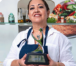 Petra Godoy ganadora del Premio Emprendedores 2024, sosteniendo el trofeo en un restaurante.